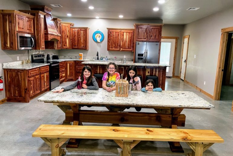 4 girls on the large dining table with the stocked kitchen at Lake Texoma Luxury Rentals