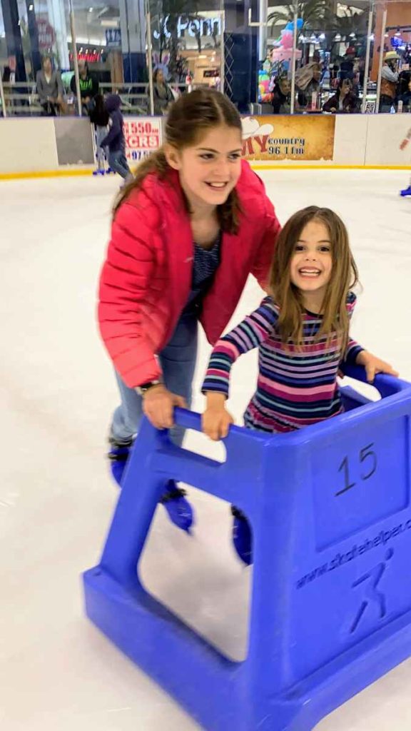 little girl and her sister ice skating at MCM in Odessa