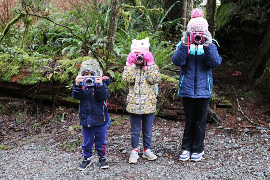 three kids taking pictures with a camera
